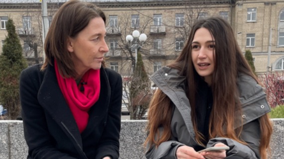 The BBC's Sarah Rainsford sits on a street in Ukraine with Lyudmila Plachkov, whose parents went missing after Russia's invasion.