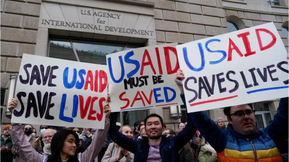 Protesters hold banners with the slogam US AID saved lives