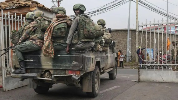 A group of people in camouflage clothes and helmets are carried on the back of a pickup truck