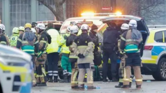 A group of first respondents stand by their cars near the Risbergska school