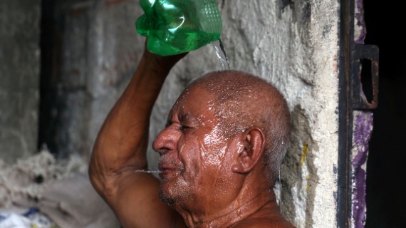 A man pour water on himself from the bottom half of a cut out plastic water bottle