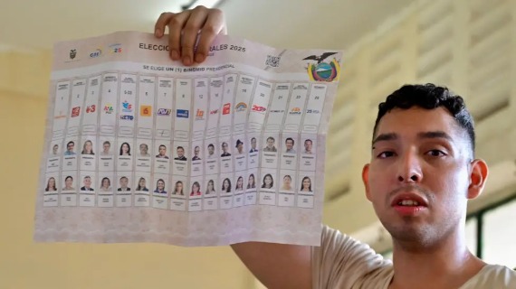 A young man holds up a ballot paper featuring more than a dozen parties.