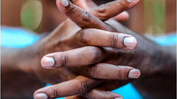 Two hands interlock, the nails prominently displayed.