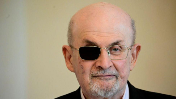 A headshot of Salman Rushdie wearing glasses with one lense covered over his blinded eye