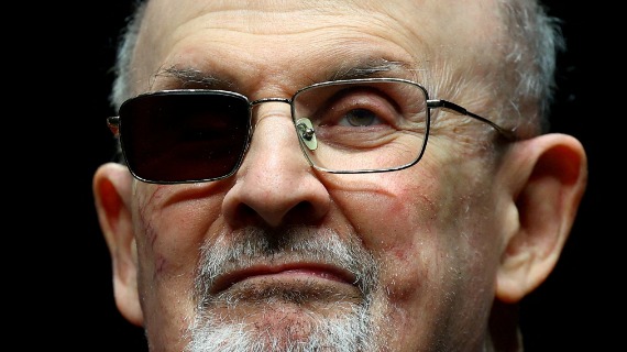 a close up photograph of Salman Rushdie, with one lense of his glasses blacked out