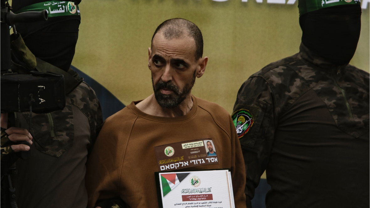 Two Hamas fighters in green combat gear and masks flank Eli Sharabi, an emaciated Israeli hostage who has had his head shaved.